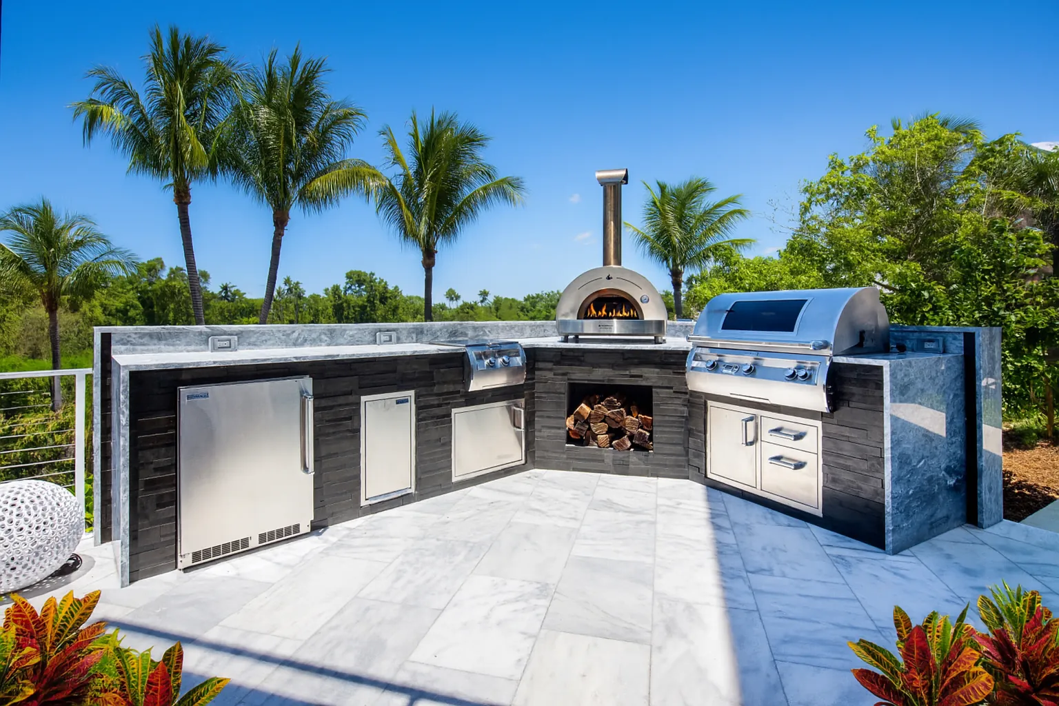 Coastal outdoor kitchen with pizza oven and grill island by Knäak, Naples Florida